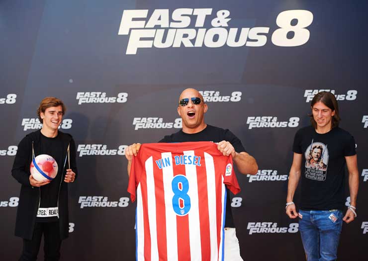 Charlize Theron in Gucci and Vin Diesel were delighted to “sign” for Atlético Madrid as the two Fast & Furious: Fate of the Furious stars were presented with the red and white soccer shirts in Madrid, Spain by Antoine Griezmann and Filipe Luis