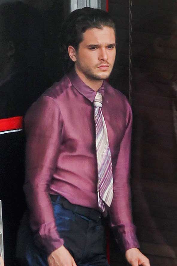 Kit Harington pictured on set of The Death and Life of John F. Donovan wearing a shiny purple silk purple shirt and blue trousers © Atlantic Images