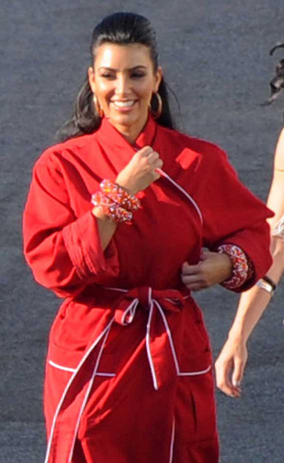A smiling Kim Kardashian matched her dressing gown with oversized earrings and a red bow in her hair