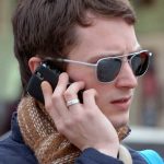 wearing silver ring sunglasses Elijah Wood makes a phone call on iphone