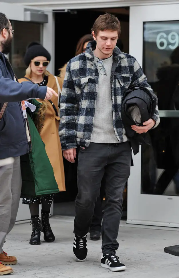 Evan Peters carried his coat leading the way with fiancee Emma Roberts behind him in a cute beanie American Animals