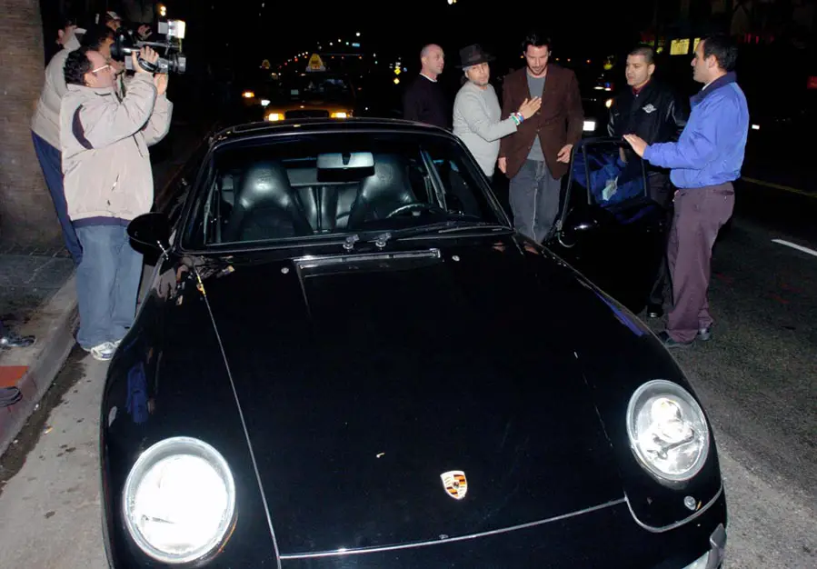 Keanu Reeves is guided into his Porsche 911 sports car in Hollywood, Los Angeles