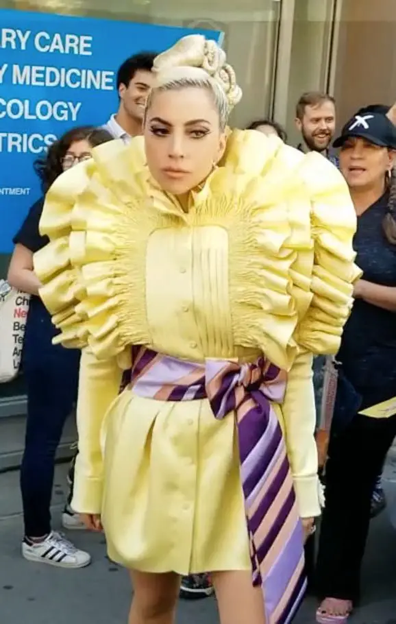 Lady Gaga wears a bright yellow Viktor&Rolf ruffled shirt dress form their Spring Couture collection and a pink and blue bow tie belt © The MEGA Agency