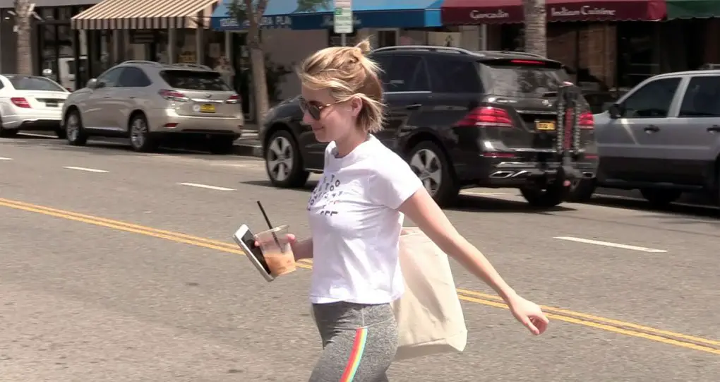 Emma Roberts pictured with her iced drink and phone in one hand wearing her Spiritual Gangster Yoga rainbow leggings © The MEGA Agency