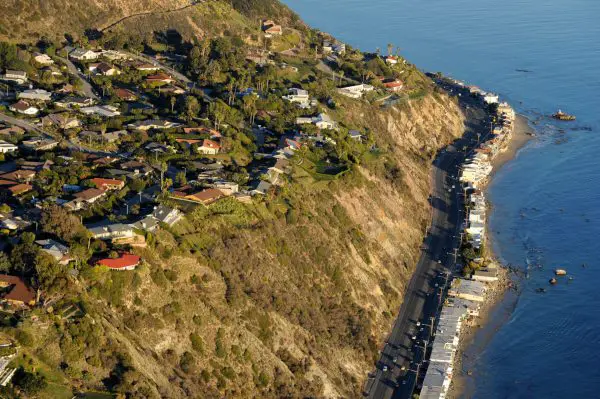 Pictured is the Pacific Coast Highway in Malibu, California which is home to the rich and famous. Downtown Los Angeles can be seen in the distance. The highway is famous for running along some of the most beautiful coastlines in the USA, leading to its designation as an All-American Road. In addition to providing a scenic route to numerous attractions along the coast, the route also serves as a major thoroughfare in the Greater Los Angeles Area, the San Francisco Bay Area and several other coastal urban areas.
